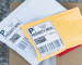 Standard white and yellow Priority Mail packages with generic thermal labels, illustrating a typical unboxing experience without decorative stamps.