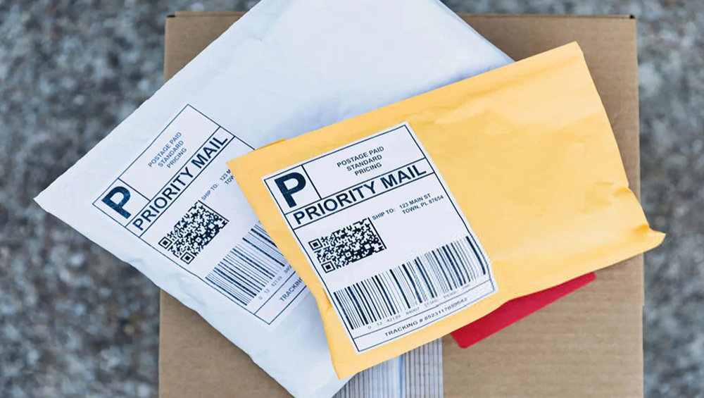 Standard white and yellow Priority Mail packages with generic thermal labels, illustrating a typical unboxing experience without decorative stamps.